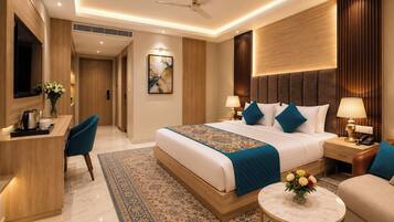 A hotel room with a bed, bedside tables, a desk, a chair, a round table, and a ceiling fan.