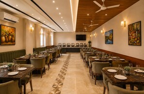 A hotel dining area with multiple tables, chairs, and a central buffet. - Hotel West End Mahipalpur Delhi IGI (New Delhi)