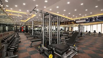 A gym with various exercise equipment, mirrors, and a tiled floor.