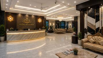 A hotel lobby with a reception desk, seating area, and a chandelier.