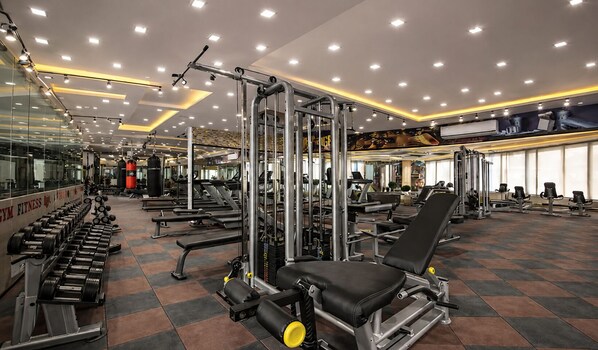 Kuntosali, jossa on monenlaisia kuntoilulaitteita, peilejä ja laattalattia.