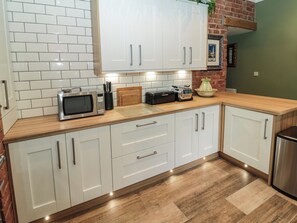 Eine moderne Küche mit weißen Schränken, einer Mikrowelle, einem Toaster und einer Wand mit Backsteinverkleidung.