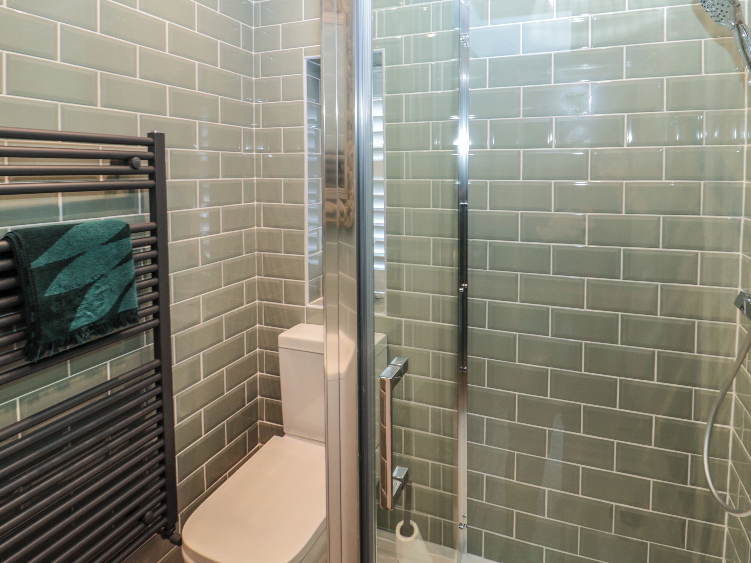 A bathroom with a glass shower enclosure, a towel rack with a towel, and a toilet.