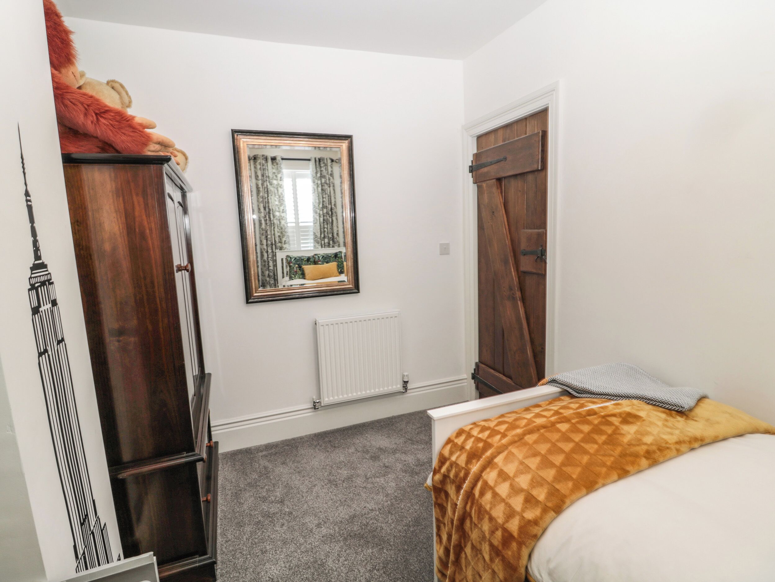 Un dormitorio con cama, armario, espejo y radiador.