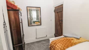 Un dormitorio con cama, armario, espejo y radiador.