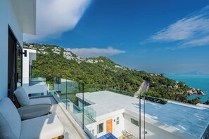 A modern balcony with a glass railing overlooking a coastal landscape.