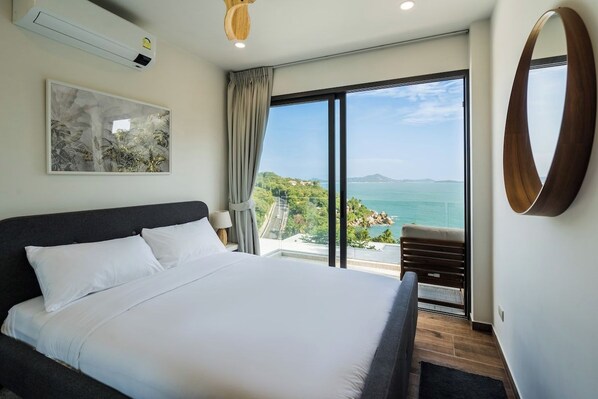 A hotel room with a large bed, a view of the sea, and a painting on the wall.
