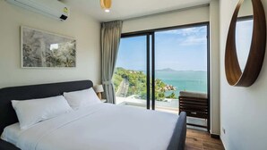 A modern bedroom with a large bed, a view of the sea, and a balcony.