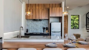 A modern kitchen with wooden cabinets, a central island with bar stools, and pendant lighting.