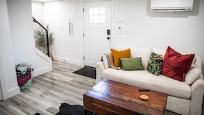 Ein Wohnzimmer mit einem weißen Sofa, einem Holztisch und einer Treppe, die in einen anderen Raum führt.