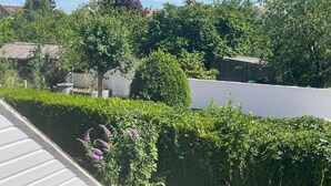 Een woongebied met een wit gebouw, groene bomen en een helderblauwe lucht.