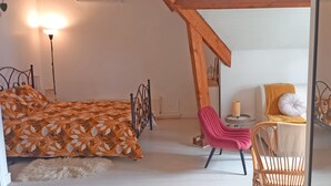 Een slaapkamer met een bed, een stoel, een kleine tafel en een lamp.