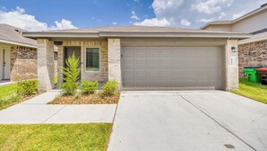 A modern two-story house with a garage, brick exterior, and a small front yard with plants. - Stunning Modern beautiful home! (Spring)