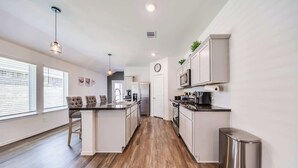 A modern kitchen with white cabinetry, stainless steel appliances, and a central island. - Stunning Modern beautiful home! (Spring)
