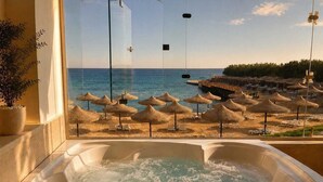 Un bain à remous avec vue sur une plage parsemée de parasols et de chaises longues.