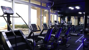Une salle de sport équipée de tapis de course, d’appareils de marche en escalier et d’autres équipements d’exercice.