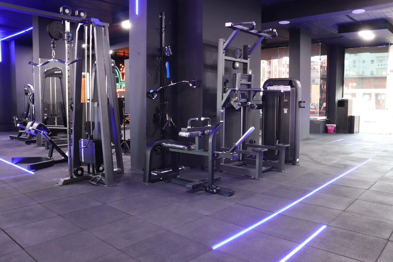 A gym with various exercise machines, a mirrored wall, and a tiled floor.