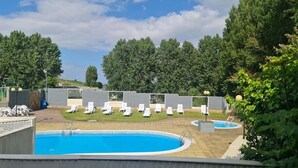 Een zwembad met ligbedden en een kleine jacuzzi.