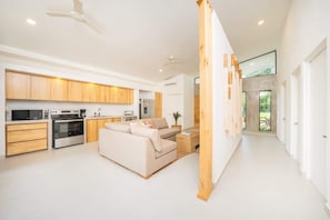 A modern kitchen with wooden cabinets, a built-in oven, and a dining area with a sofa and coffee table.