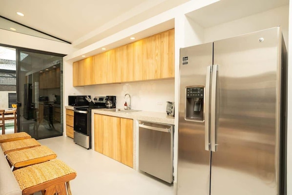 A modern kitchen with wooden cabinets, stainless steel appliances, and a built-in dishwasher.