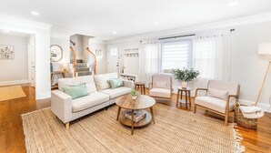 Un salon spacieux comprenant un grand canapé, deux fauteuils, une table basse et un escalier menant à un autre niveau.