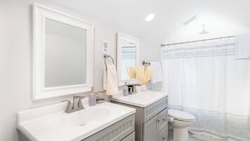 A modern bathroom with a double sink vanity, a toilet, and a shower curtain.