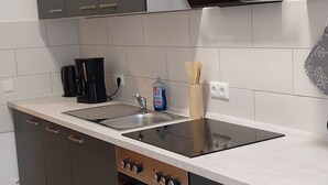 A modern kitchen with grey cabinets, a stainless steel sink, and a built-in oven. - Vacation apartment "Mittags-Ruh" in the center of Reichenbach/Vogtland. (Reichenbach im Vogtland)