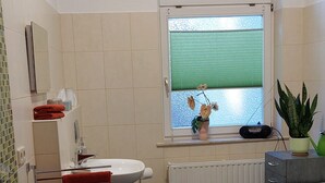 A modern bathroom with a toilet, sink, and a window with a view. - Vacation apartment "Mittags-Ruh" in the center of Reichenbach/Vogtland. (Reichenbach im Vogtland)