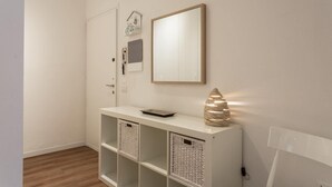 A hallway with a white console table, wicker baskets, a framed mirror, and a wall-mounted light fixture. - Peschierahome - Arilica (Peschiera del Garda)