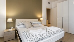 A neatly made bed with a floral bedspread, two bedside lamps, and a nightstand with drawers. - Il Mincio - Peschierahome (Peschiera del Garda)