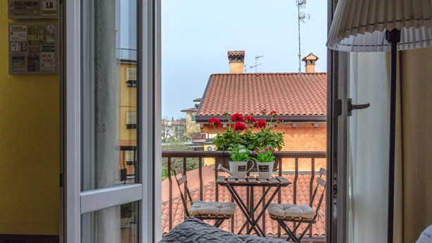 A balcony with a table, two chairs, and potted plants. - La Rocca - Peschierahome (Peschiera del Garda)