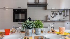 A modern kitchen with stainless steel appliances, a gas stove, and a range hood. There are two potted plants on the counter, and various kitchen utensils and cookware hanging on the wall. - La Rocca - Peschierahome (Peschiera del Garda)