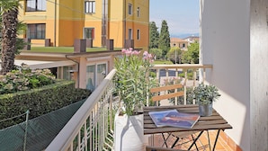 A balcony with a wooden table, a potted plant, and a magazine.
