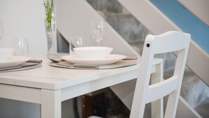 Una mesa de comedor blanca con platos, vasos y un florero con flores.