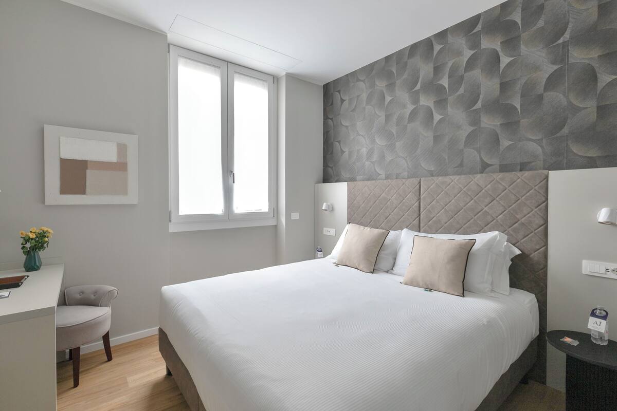 Una habitación de hotel moderna con una cama grande, un escritorio y una ventana.