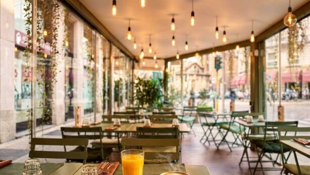 Un café en plein air avec des tables, des chaises et un croissant posé sur l’une des tables.