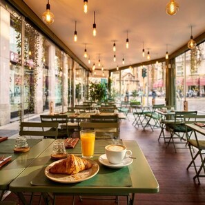 Un café en plein air avec des tables, des chaises et un croissant posé sur l’une des tables.
