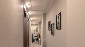 Un couloir au design moderne, avec un long passage, un coin repas à l’arrière-plan et trois œuvres d’art abstraites accrochées au mur.