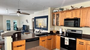 A modern kitchen with granite countertops, wooden cabinets, a built-in microwave, and a stainless steel oven.