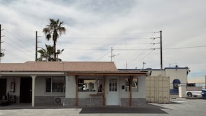 A small building with a tiled roof, a front door, and a small porch. - Border Motel (Calexico)