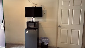 A compact kitchenette with a refrigerator, microwave, and a small TV mounted on the wall. - Border Motel (Calexico)