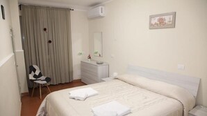 Een slaapkamer met een bed, een stoel, een kaptafel en een spiegel.