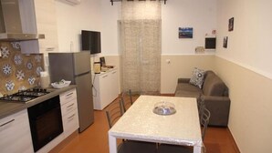 Een kleine keuken met een eettafel, stoelen, een bank en een televisie.