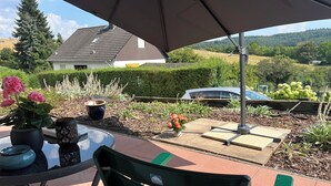 An outdoor patio with a table, chairs, and a large umbrella. - Apartment GoodTimes, ground floor, 2 x 50" TV, Netflix, south-facing terrace w. Access to the parking lot (Aarbergen)
