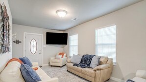 A living room with a beige sofa, a white armchair, and a patterned rug. - Remote private fishing getaway! (Chico)