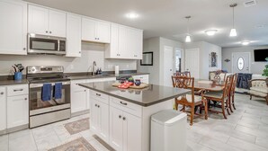 A modern kitchen with white cabinetry, stainless steel appliances, and a central island with seating. - Remote private fishing getaway! (Chico)