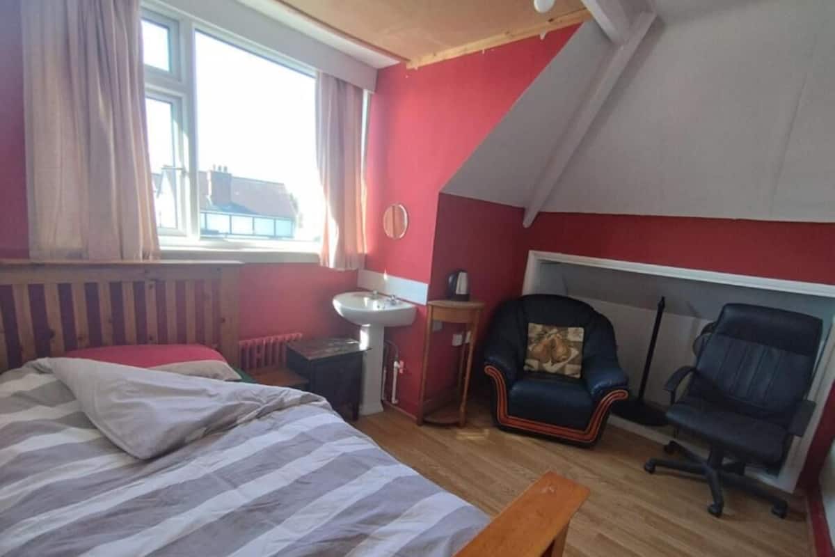 Una camera da letto con un letto, una scrivania, una sedia, un termosifone e una finestra.