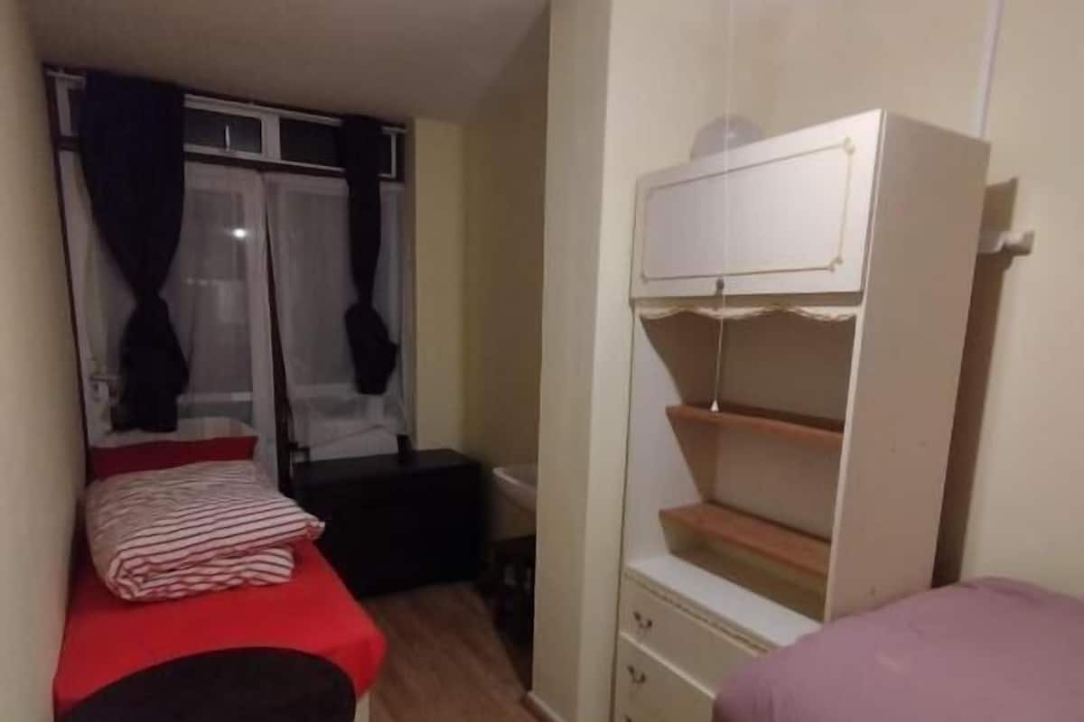 Una stanza piccola con un letto a castello, una scrivania e una sedia.