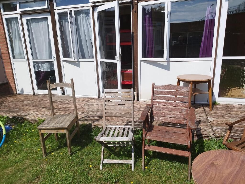 Une terrasse avec des chaises et une table en bois, une porte-fenêtre coulissante et un mur en briques.