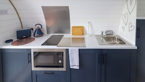 Una cocina moderna con armarios oscuros, una encimera blanca, un microondas, un tostador y un fregadero.